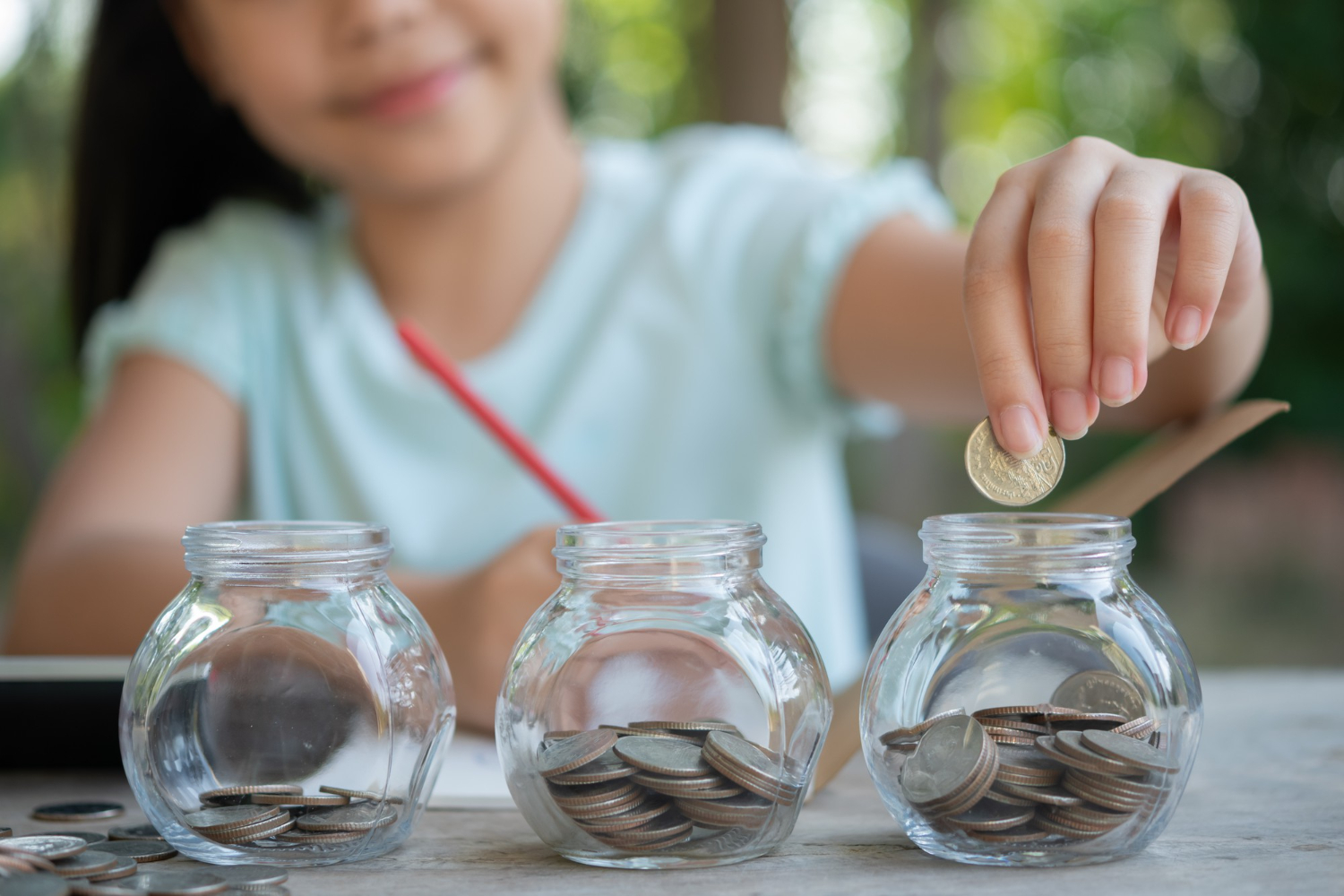 girl playing with coins making stacks money kid saving money into piggy bank into glass jar