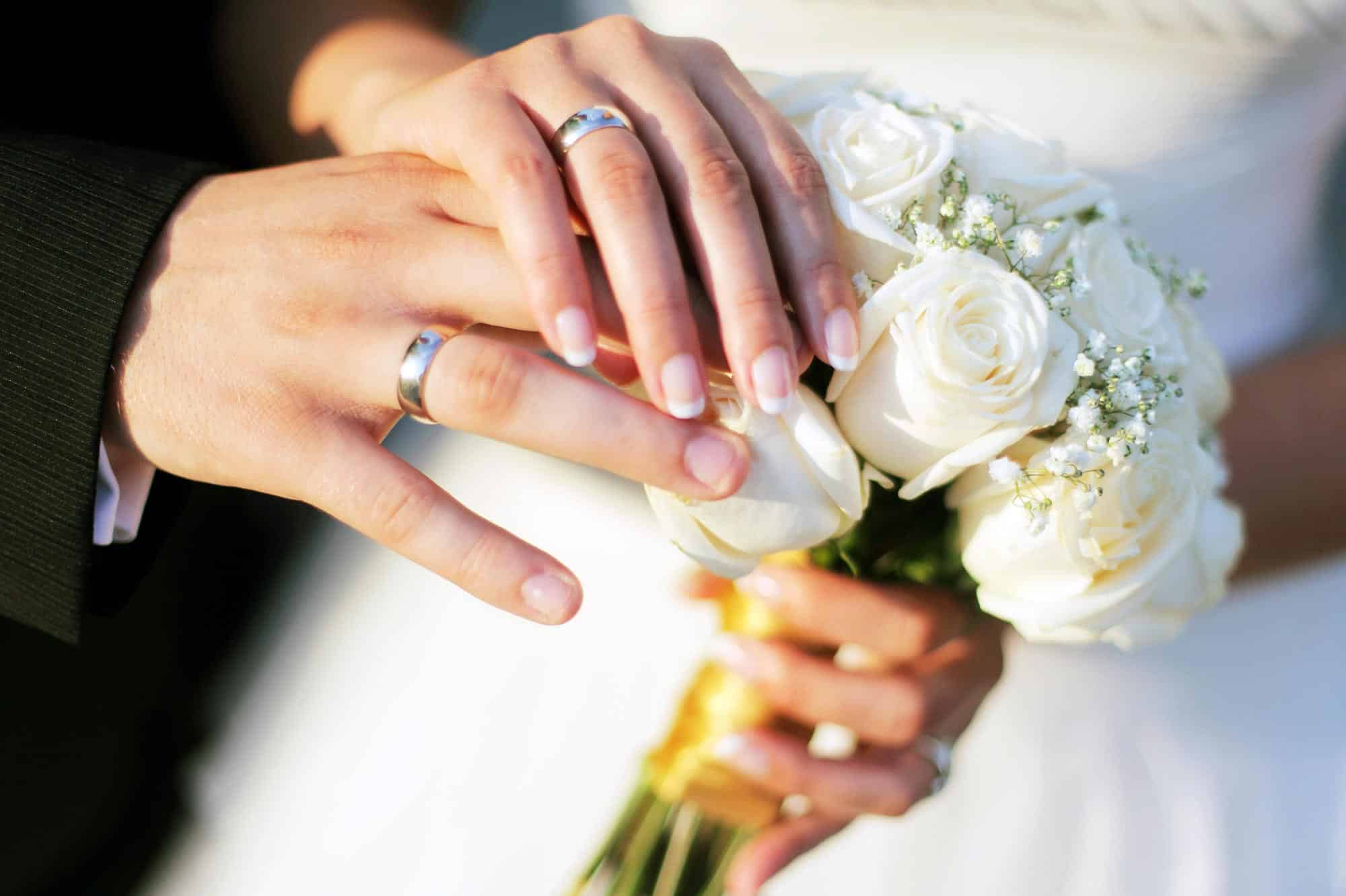 hands wedding rings bouquet roses